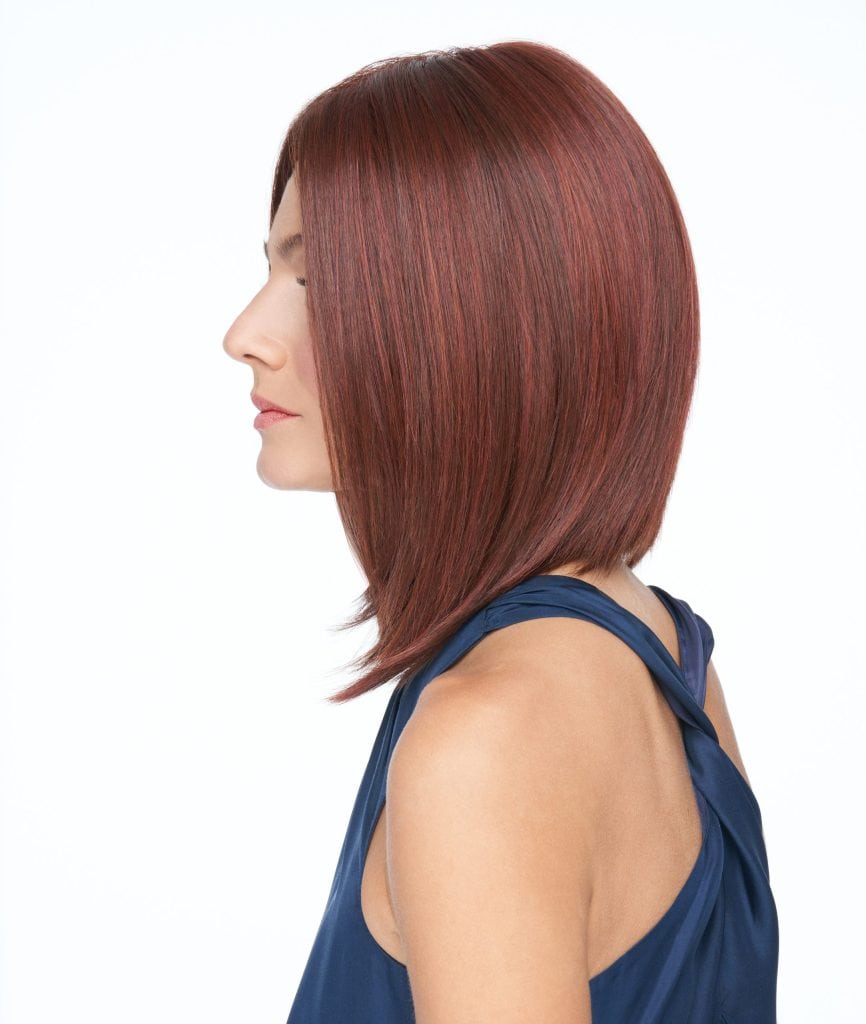 Side view of a woman with a sleek, straight red bob wig.