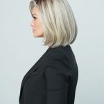 Side view of a woman with a sleek blonde bob wig and black blazer.
