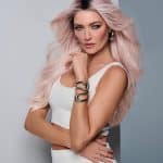 Woman with long pink hair and stylish makeup, wearing a white top.