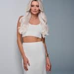 Blonde wavy wig on a woman with a white outfit and soft makeup.