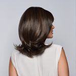 Side view of a woman with a brown layered wig, styled with soft waves.