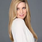 Blonde wig with layered style on a woman with blue eyes and a white top.