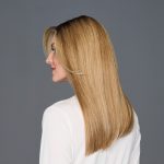 Side view of a woman with straight blonde wig against gray background.
