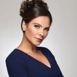 Woman with elegant curly updo wig in navy blue dress.