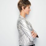 Side view of a woman with a short, layered pixie wig in light brown.