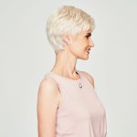 Side view of a woman with short, silver wig and light pink sleeveless top.