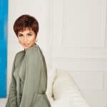 Woman with short red wig and stylish outfit in modern room.