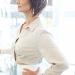 Side view of woman with short layered wig in a bright room.