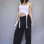 Fashion model wearing a white crop top and black wide-leg pants.