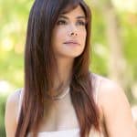 Woman with long, straight, brown hair in an outdoor setting.