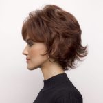 Side view of a woman with a short, layered auburn wig from Hidden Secrets Wigs.