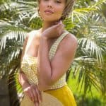 Woman with short blonde wig in tropical garden for Hidden Secrets Wigs.