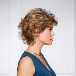 Curly short wig in light brown on a woman with side profile.