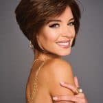 Woman with short, layered brown wig and bright smile.