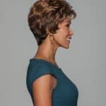 Woman with short, curly, layered wig in a side profile view.