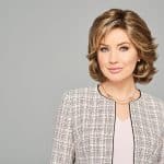 Woman with a stylish wavy bob wig, wearing a checkered blazer and light blouse.