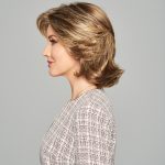 Side view of a woman with a layered, blonde wig styled in a voluminous bob.