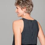 Short gray curly wig styled on a smiling woman with earrings.