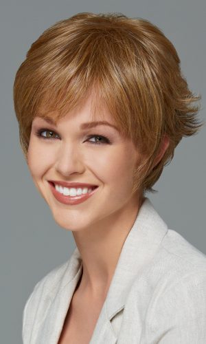 Woman with short, layered, light brown wig smiling at camera.