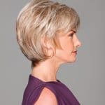 Side view of a woman wearing a short, layered blonde wig with a purple top.