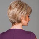 Side view of a short blonde wig on a woman with a purple top.