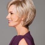 Side view of a woman with a stylish short blonde wig and hoop earrings.