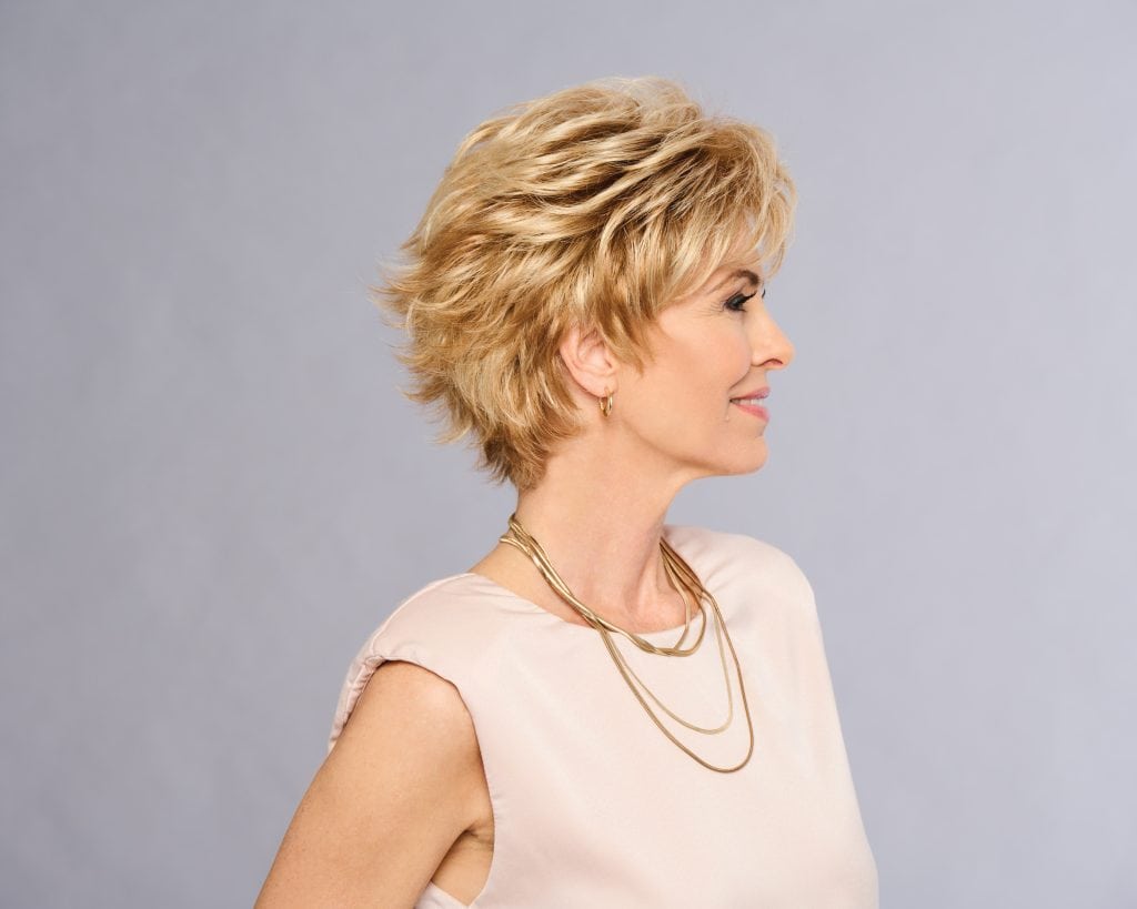 Short blonde wig styled on a mature woman with layered hair and side-swept bangs.