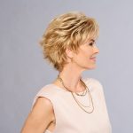 Short blonde wig styled on a mature woman with layered hair and side-swept bangs.