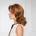 Side view of a woman with auburn wavy wig and stylish outfit.