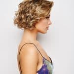 Stylish curly blonde wig on a woman with short hair and side profile.