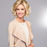 Blonde curly wig styled on smiling woman with short hair.