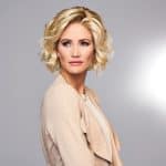 Blonde curly wig styled on a woman with short hair and natural makeup.