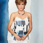 Elegant woman with short layered wig, wearing stylish jewelry and a patterned top.
