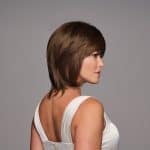 Side view of a woman with a sleek brown bob wig and white top.