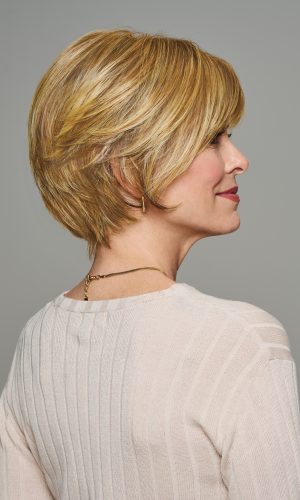 Side view of a woman wearing a short blonde wig with layered styling.