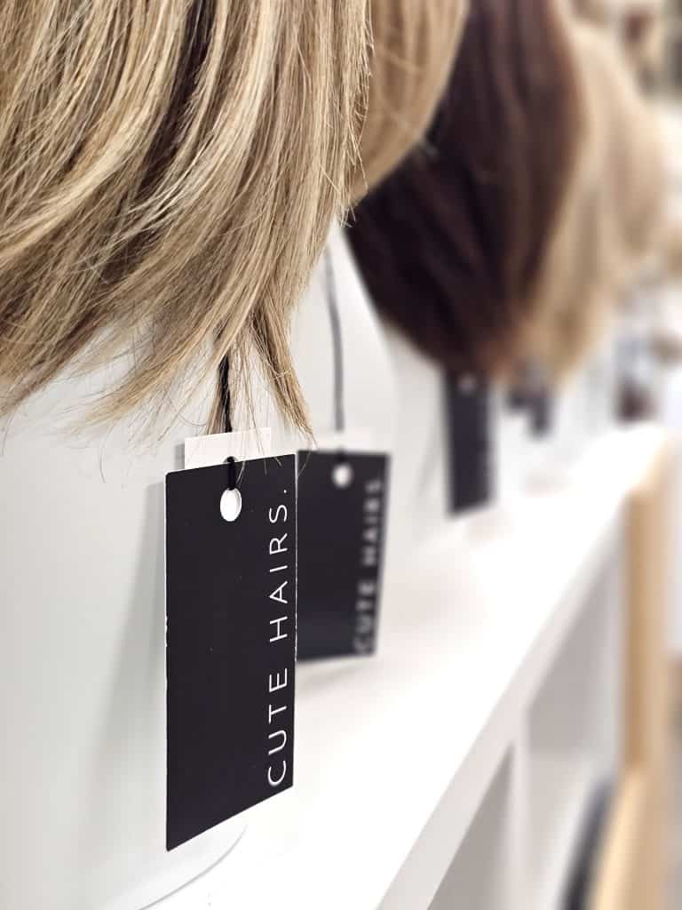 Wigs on display with tags at Hidden Secrets Wigs store.