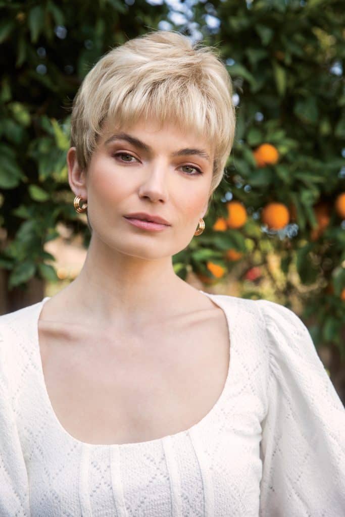 Short blonde wig with layered style on a woman outdoors.