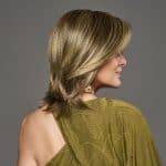 Side view of a woman with a layered blonde wig and a green top.