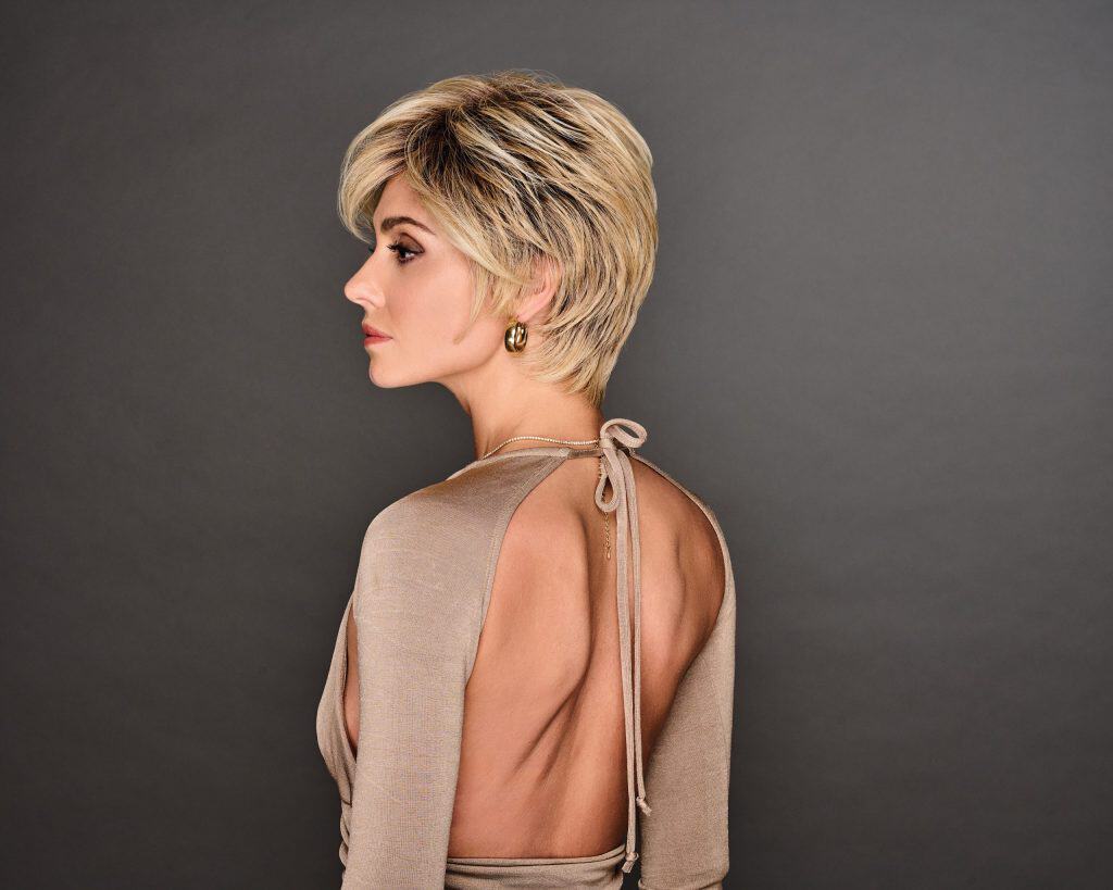 Short blonde wig styled on a woman with a backless beige dress.