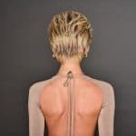 Back view of a woman with short blonde wavy wig and stylish earrings.