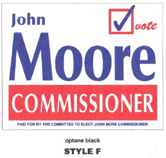 Political campaign sign for John Moore, Commissioner, with checkmark and red and blue colors.
