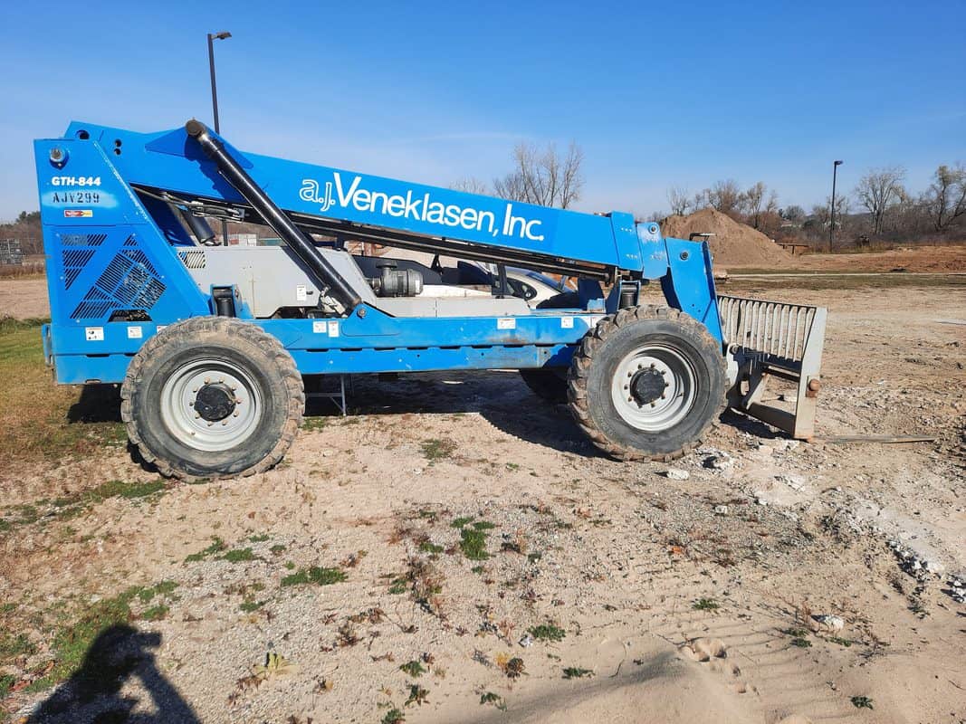 Blue aerial work platform with Veneklasen Inc. branding on a construction site.