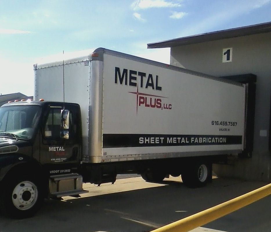 Delivery truck for Metal Plus LLC parked outside a building.