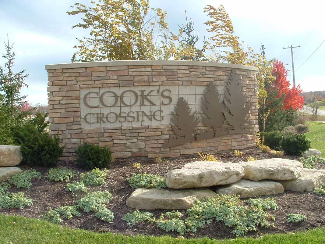 Handicap parking sign at Cook's Crossing with trees and landscaping.