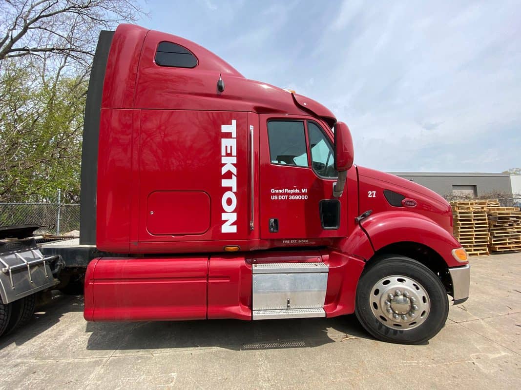 Red Tekton semi-truck with company branding in an outdoor lot.