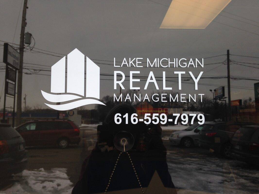 Lake Michigan Realty Management sign on glass window with contact number.