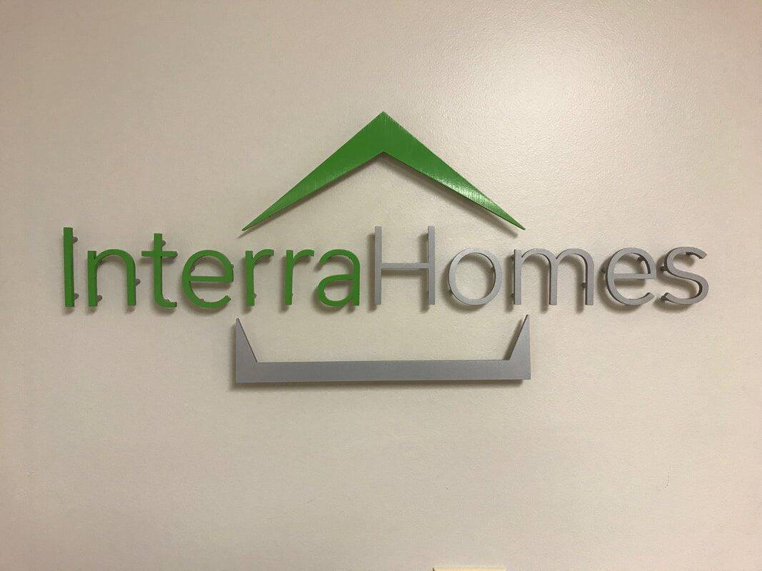 Interra Homes logo with green roof graphic and gray text on wall.