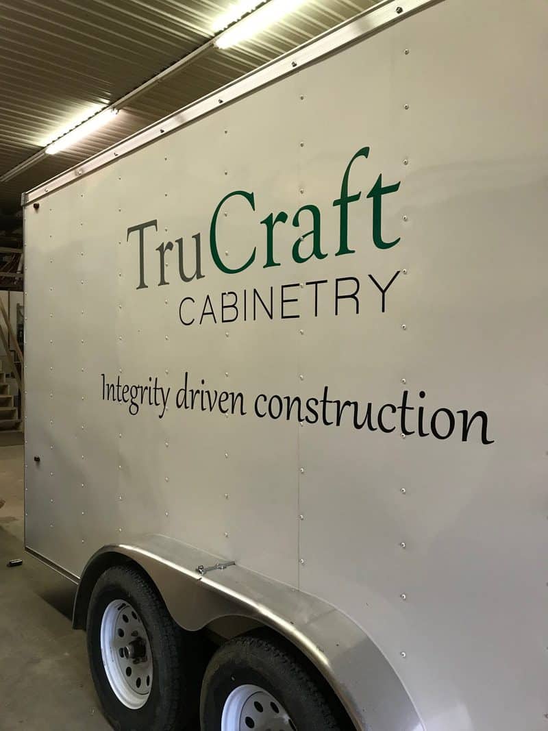 TruCraft Cabinetry sign on a white trailer in warehouse setting.