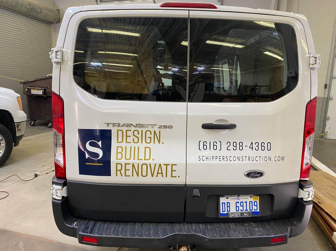 White Ford Transit van with company logo and contact info on the back.