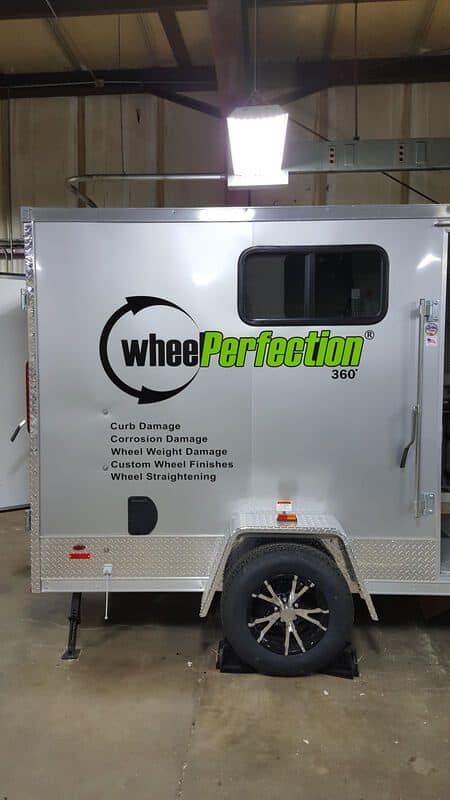 Mobile wheel repair trailer with WheelPerfection branding and a small window.